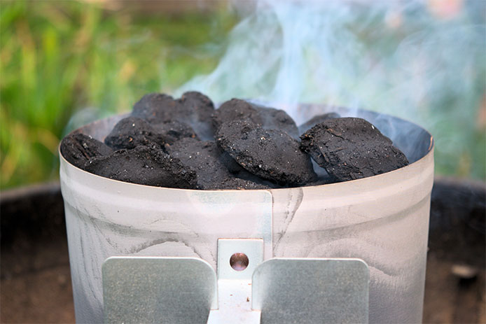 Charcoal in chimney starter with smoke rising through