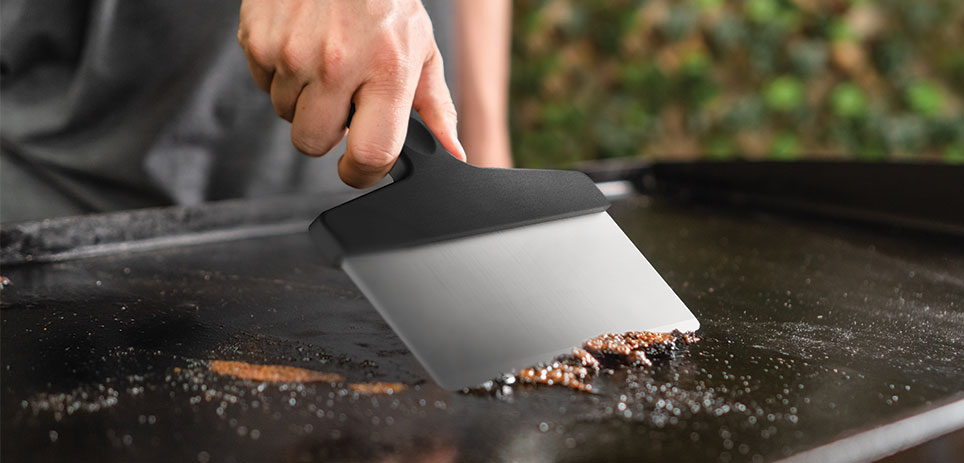 Man scraping off griddle with spatula